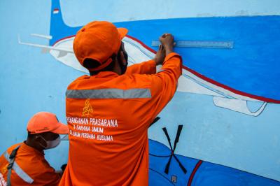 Petugas Penanganan Prasarana dan Sarana Umum (PPSU) menyelesaikan mural di tembok kawasan Halim Perdanakusuma, Jakarta, Rabu (21/6/2021).