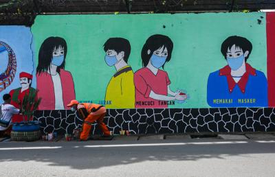 Petugas Penanganan Prasarana dan Sarana Umum (PPSU) menyelesaikan mural di tembok kawasan Halim Perdanakusuma, Jakarta, Rabu (21/6/2021).