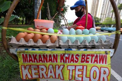 Pedagang sedang membuat kerak telor makanan khas Betawi yang masih bertahan dimasa pandemi di kawasan Kemayoran, Jakarta Pusat, Selasa (22/6/2021).