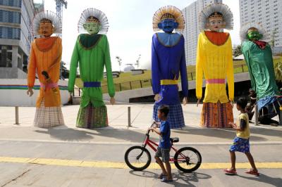 Pejalan kaki melintas di dekat pameran ondel-ondel berukuran rakasa di kawasan Taman Ismail Marzuki (TIM), Jakarta, Selasa (22/6/2021).