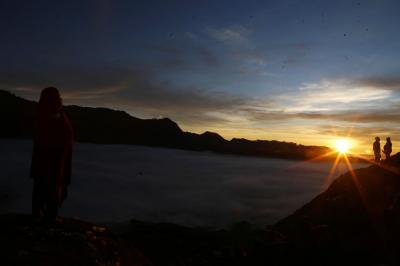 Warga Tengger menanti matahari terbit di bibir kawah Gunung Bromo pada perayaan Yadnya Kasada tahun ke 1943 Saka di Probolinggo, Jawa Timur, Sabtu (26/6/2021).