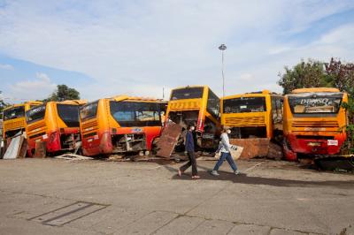 Pejalan kaki melintas di dekat rongsokan bus Transjakarta di Terminal Pulogadung, Jakarta Timur, Minggu (27/6/2021).