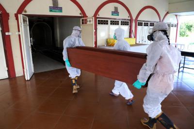 Petugas Krematorium mengenakan Hazmat dan APD memasukkan peti jenazah kedalam tungku pembakaran di Krematorium Keputih, Surabaya, Selasa (29/6/2021).
