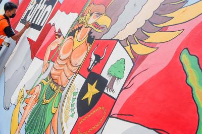 Petugas saat melukis mural ditembok di kawasan Jakarta Pusat, Selasa (29/6/2021).