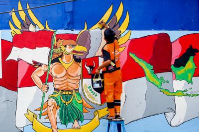 Petugas saat melukis mural ditembok di kawasan Jakarta Pusat, Selasa (29/6/2021).