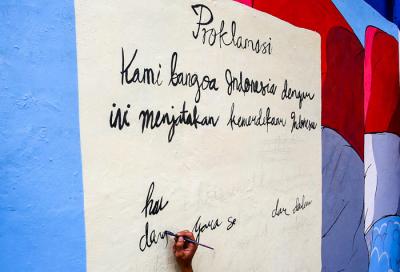 Petugas saat melukis mural ditembok di kawasan Jakarta Pusat, Selasa (29/6/2021).