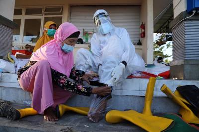Para Modin saling membantu mengenakan alat pelindung diri (APD) lengkap di tempat pemulasaraan darurat Keputih Surabaya, Rabu (30/6/2021).