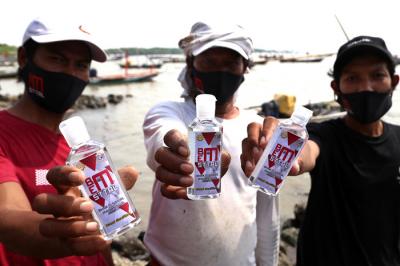 Pembagian masker dan hand sanitizer pada nelayan dan masyarakat di jalur pintu Jembatan Suramadu, Kenjeran Surabaya, Jawa Timur, Jumat (2/7/2021).