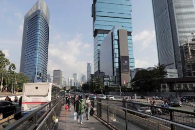 Sejumlah pekerja berjalan di jalur pedestrian Jalan Jenderal Sudirman, Jakarta, Jumat (2/7/2021).