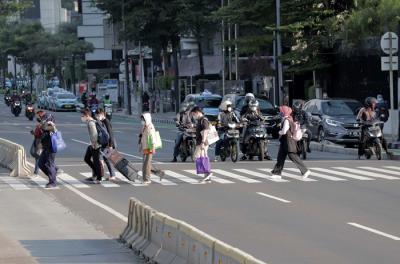 Sejumlah pekerja berjalan di jalur pedestrian Jalan Jenderal Sudirman, Jakarta, Jumat (2/7/2021).