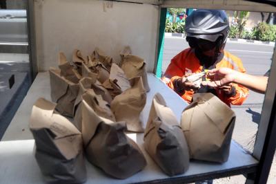 Warga mengambil nasi bungkus gratis didepan salah satu pertokoan di kawasan Jalan Ngagel, Surabaya, Jawa Timur, Minggu (4/7/2021).