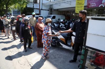 Warga mengambil nasi bungkus gratis didepan salah satu pertokoan di kawasan Jalan Ngagel, Surabaya, Jawa Timur, Minggu (4/7/2021).