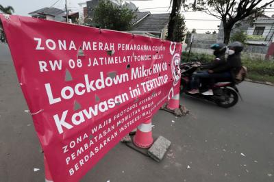 Pengendara melintasi spanduk bertuliskan Lockdown Mikro RW 08 Kawasan Ini Tertutup di kawasan Puri Gading, Kota Bekasi, Jawa Barat, Senin (5/7/2021).
