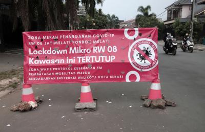 Pengendara melintasi spanduk bertuliskan Lockdown Mikro RW 08 Kawasan Ini Tertutup di kawasan Puri Gading, Kota Bekasi, Jawa Barat, Senin (5/7/2021).