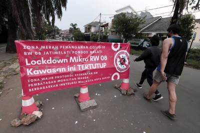 Pengendara melintasi spanduk bertuliskan Lockdown Mikro RW 08 Kawasan Ini Tertutup di kawasan Puri Gading, Kota Bekasi, Jawa Barat, Senin (5/7/2021).