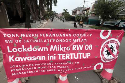 Pengendara melintasi spanduk bertuliskan Lockdown Mikro RW 08 Kawasan Ini Tertutup di kawasan Puri Gading, Kota Bekasi, Jawa Barat, Senin (5/7/2021).