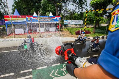 Petugas Pemadam Kebakaran meyemprotkan cairan disinfektan ke pengendara di Jalan Raya Lenteng Agung, Jakarta Selatan, Senin (5/7/2021).
