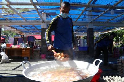 Para relawan memasak di dapur umum Kementerian Sosial di area halaman Convention Hall Surabaya, Jawa Timur, Senin (5/7/2021).