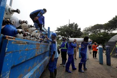 Sejumlah petugas menurunkan tabung berisi oksigen dari truk di Posko Darurat Oksigen Rescue di kawasan Monumen Nasional, Jakarta, Senin (5/7/2021).