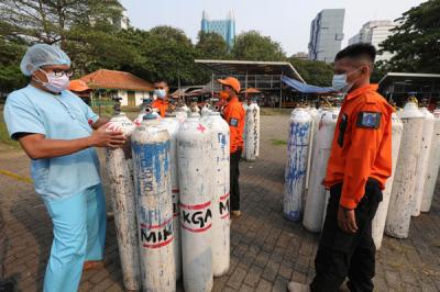 Sejumlah petugas menurunkan tabung berisi oksigen dari truk di Posko Darurat Oksigen Rescue di kawasan Monumen Nasional, Jakarta, Senin (5/7/2021).