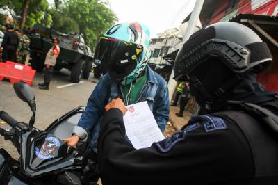 Petugas Brimob saat melakukan pemeriksaan warga yang melewati pos penyekatan PPKM Darurat di Lenteng Agung, Jakarta Selatan, Selasa (6/7/2021).