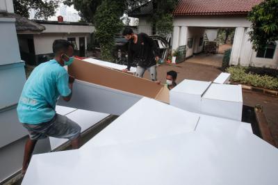 Pekerja mengangkat peti mati untuk dipindahkan ke ambulans di TPU Petamburan, Jakarta Pusat, Selasa (6/7/2021).