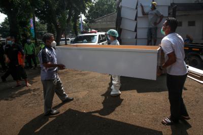 Pekerja mengangkat peti mati untuk dipindahkan ke ambulans di TPU Petamburan, Jakarta Pusat, Selasa (6/7/2021).