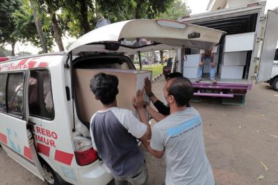 Pekerja mengangkut peti jenazah ke dalam ambulans untuk didistribusikan di TPU Petamburan, Jakarta Pusat, Selasa (6/7/2021).