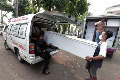Pekerja mengangkut peti jenazah ke dalam ambulans untuk didistribusikan di TPU Petamburan, Jakarta Pusat, Selasa (6/7/2021).