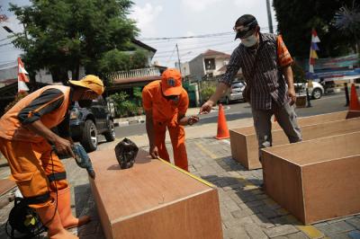 Petugas PPSU menyelesaikan pengerjaan peti jenazah untuk pasien Covid-19 di Kantor Kelurahan Kayu Putih, Jakarta, Selasa (6/7/2021).