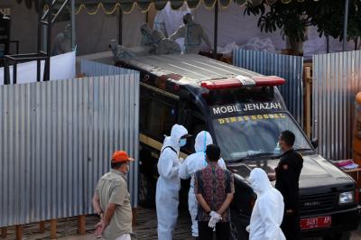 Petugas mengangkat peti jenazah untuk dilakukan perawatan sebelum di makamkan di tempat pemulasaraan darurat Keputih Surabaya, Jawa Timur, Kamis (8/7/2021).