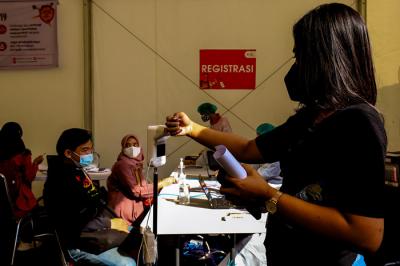 Petugas Palang Merah Indonesia menyuntikan vaksin Covid-19 kepada warga saat vaksinasi massal di Gudang Darurat Nasional, Jakarta Selatan, Jumat (9/7/2021).