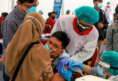 Petugas Palang Merah Indonesia menyuntikan vaksin Covid-19 kepada warga saat vaksinasi massal di Gudang Darurat Nasional, Jakarta Selatan, Jumat (9/7/2021).
