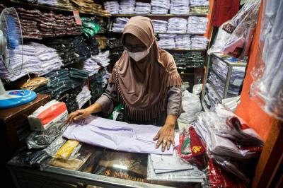 Pedagang saat merapihkan seragam sekolah di toko perlengkapan sekolah di Pasar Pal, Depok, Jawa Barat, Jumat (9/7/2021).