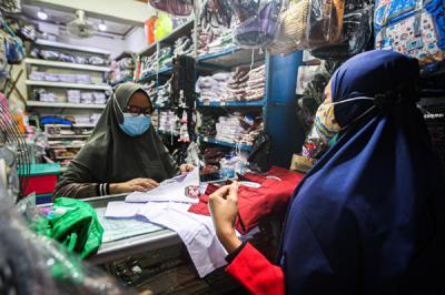 Pedagang saat merapihkan seragam sekolah di toko perlengkapan sekolah di Pasar Pal, Depok, Jawa Barat, Jumat (9/7/2021).