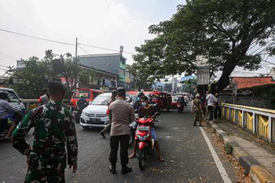 Petugas memeriksa KTP warga yang ingin melewati penyekatan di Jalan Molek, Pondok Gede, Kota Bekasi, Jawa Barat, Minggu (11/7/2021).