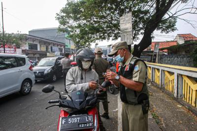Petugas memeriksa KTP warga yang ingin melewati penyekatan di Jalan Molek, Pondok Gede, Kota Bekasi, Jawa Barat, Minggu (11/7/2021).