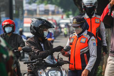 Petugas memeriksa KTP warga yang ingin melewati penyekatan di Jalan Molek, Pondok Gede, Kota Bekasi, Jawa Barat, Minggu (11/7/2021).