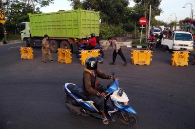 Petugas mengarahkan pengendara untuk putar balik saat akan masuk kota Surabaya melalui akses masuk dari Surabaya Timur di Jawa Timur, Senin (12/7/2021).