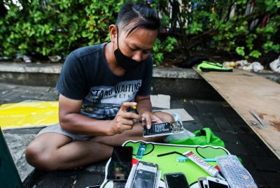 Tukang service Handphone menawarkan jasanya dipinggir jalan di kawasan Cililitan, Jakarta Timur, Senin (12/7/2021).