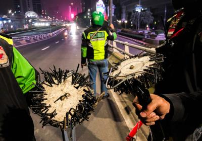Driver Ojek Online yang tergabung dalam komunitas Tebar saat mencari ranjau paku yang bertebaran di Jalan Gatot Subroto, Jakarta, Selasa (13/7/2021).