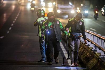 Driver Ojek Online yang tergabung dalam komunitas Tebar saat mencari ranjau paku yang bertebaran di Jalan Gatot Subroto, Jakarta, Selasa (13/7/2021).