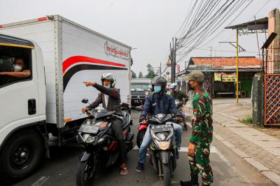 Aparat kepolisian memerksa kelengkapan surat warga saat melintas di pos penyekatan PPKM Darurat Jalan Raya Bogor, Jakarta Timur, Rabu (14/7/2021).