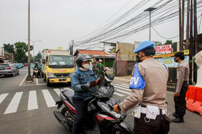 Aparat kepolisian memerksa kelengkapan surat warga saat melintas di pos penyekatan PPKM Darurat Jalan Raya Bogor, Jakarta Timur, Rabu (14/7/2021).