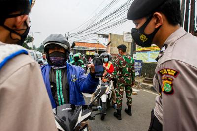 Aparat kepolisian memerksa kelengkapan surat warga saat melintas di pos penyekatan PPKM Darurat Jalan Raya Bogor, Jakarta Timur, Rabu (14/7/2021).