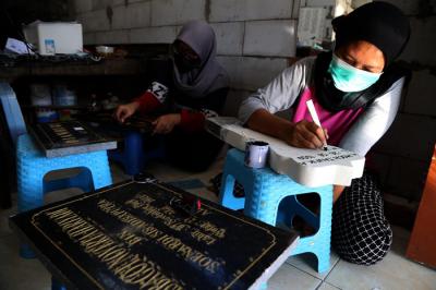 Perajin menyelesaikan pembuatan batu nisan disalah satu rumah produksi Keputih Surabaya, Jawa Timur, Jumat (16/7/2021).
