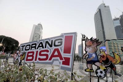 Pengendara melintas di dekat maskot dan slogan Pekan Olahraga Nasional (PON) XX Papua di Bundaran Hotel Indonesia, Jakarta, Jumat (16/7/2021).