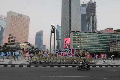 Pengendara melintas di dekat maskot dan slogan Pekan Olahraga Nasional (PON) XX Papua di Bundaran Hotel Indonesia, Jakarta, Jumat (16/7/2021).