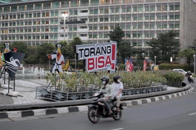 Pengendara melintas di dekat maskot dan slogan Pekan Olahraga Nasional (PON) XX Papua di Bundaran Hotel Indonesia, Jakarta, Jumat (16/7/2021).