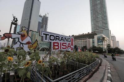Pengendara melintas di dekat maskot dan slogan Pekan Olahraga Nasional (PON) XX Papua di Bundaran Hotel Indonesia, Jakarta, Jumat (16/7/2021).